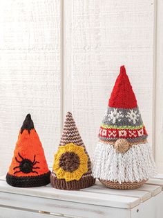 three knitted gnome hats sitting on top of a white dresser