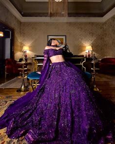 a woman in a purple dress is standing near a table with candles and chandelier