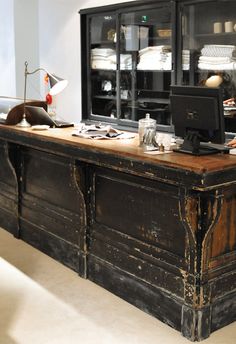 an old wooden desk with a computer monitor on it's top and shelves in the background