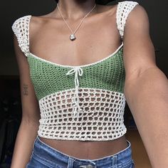 a woman wearing a green and white crochet top with her hands in her pockets