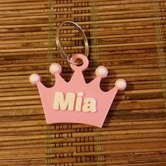 a pink keychain with the word mia on it and a crown charm attached to it