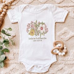 Baby Flower Bodysuit, Consider How the Wildflowers Grow, Floral Baby Christian Tee, Bible Verse Luke 12, Baby Shower Gift Looking for more inspirational apparel? Check these out: https://www.etsy.com/shop/TheGraphicPeach?ref=seller-platform-mcnav§ion_id=30193152 Our shop uses direct-to-garment printing to make our products. The design ink is sprayed on, then allowed to soak into the fibers of the garment. This process yields fine quality prints and a smooth finish on the garment. Baby clothing n Pink Cotton Onesie With Floral Print, Pink Floral Cotton Onesie, Pink Floral Print Cotton Onesie, Spring Baptism Cotton Onesie, Cotton Baptism Onesie With Short Sleeves, Fitted White Onesie With Floral Print, Flower Bodysuit, Luke 12, Baby Flower