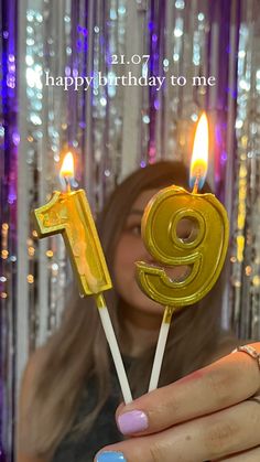 a woman holding two candles with the number nine on them