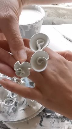 two hands are holding some white rings