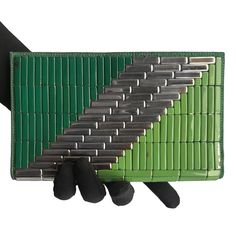 a green and black wallet with several different tools on it's back side, in front of a white background