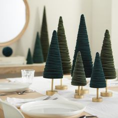 three small trees are on the table with plates and silverware in front of them