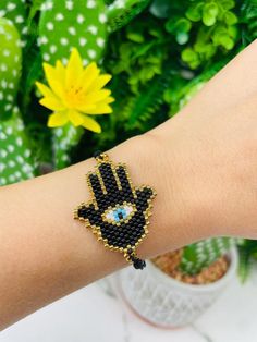 a woman's arm wearing a beaded hamsah bracelet with an evil eye on it