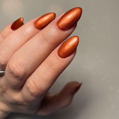 This design features a stunning metallic burnt orange shade on almond-shaped nails. The metallic finish adds a touch of shimmer and elegance, perfect for autumn evenings. The rich color combined with the glossy shine makes these nails a showstopper, ideal for those who love a bit of glam.   Photo credit by: @izabellehammonuk Rustic Orange Nails Fall, Burnt Orange Nails With Chrome, Autumn Nails Burnt Orange, Brownish Orange Nails, Chrome Burnt Orange Nails, Burnt Orange And White Nails, Orange Shimmer Nails, Rust And Gold Nails, Metallic Orange Nails