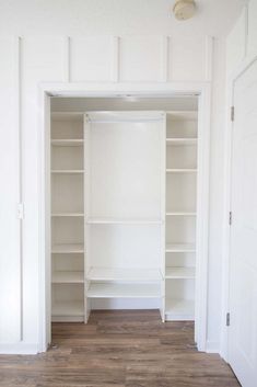 an empty walk in closet with white shelving and wood flooring on the walls