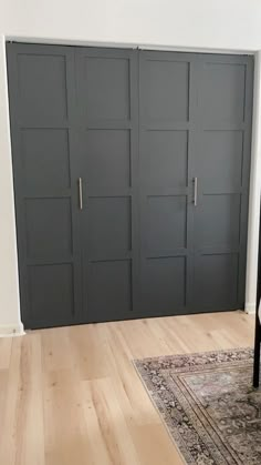 an empty room with several doors and a rug on the floor in front of it