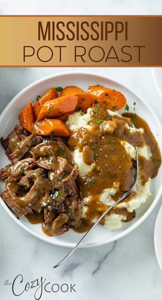 a white plate topped with mashed potatoes and meat covered in gravy next to carrots