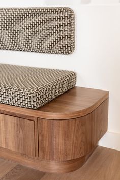 a wooden bench sitting on top of a hard wood floor next to a white wall