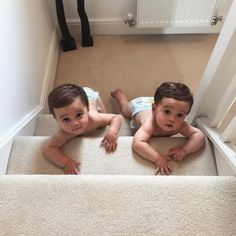 two young boys are laying on the carpet in their diapers and looking at the camera