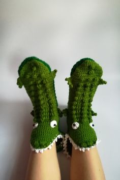 two feet wearing green crocheted slippers with eyes