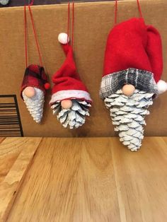 three christmas decorations are hanging on a wooden wall with pine cones and plaid hats attached to them