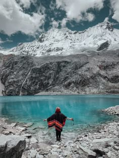 a person standing on rocks in front of a mountain lake