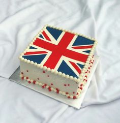 a cake decorated with the british flag is sitting on a white sheet covered tablecloth