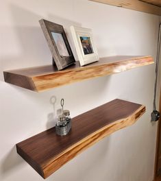 two wooden shelves on the wall with pictures and candles in them next to each other