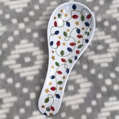 a ceramic spoon decorated with christmas lights and stars on it's side sitting on a gray surface