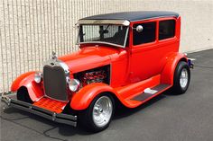 an orange classic car parked in front of a building