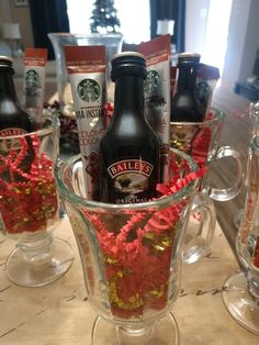 a glass cup filled with drinks on top of a table next to other cups and bottles