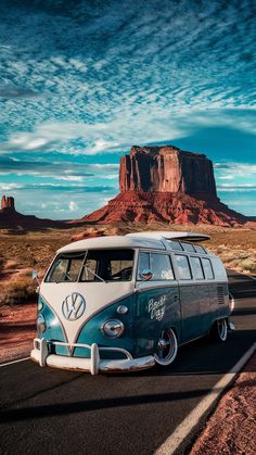 an old vw bus is parked on the side of the road in front of a mountain