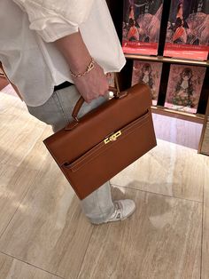 a person is holding a brown briefcase in their right hand and standing on the floor