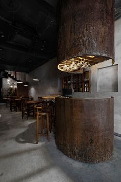 the interior of a restaurant with wooden tables and stools in front of a large metal column