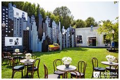 an outdoor dining area with tables, chairs and flowers in vases on the grass