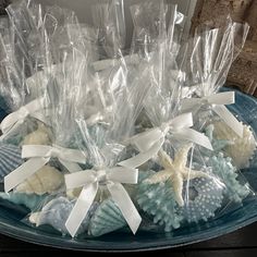 several seashells are wrapped in plastic on a blue plate with white ribbons and bows