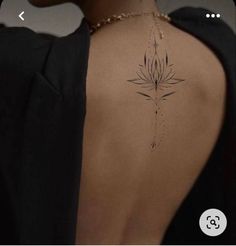 the back of a woman's neck with a flower tattoo on it