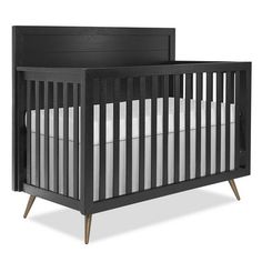 a black crib with white sheets and wood trims on the sides, in front of a white background