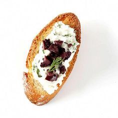 a piece of bread with cream cheese and beets on it, sitting on a white surface