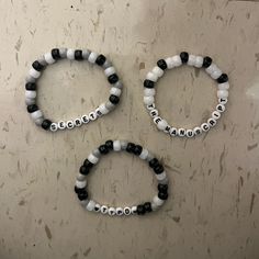 three black and white beaded bracelets with words on them sitting next to each other