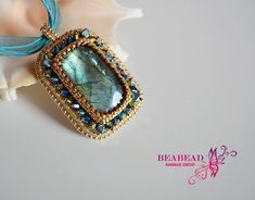 a necklace with a blue beaded pendant hanging from it's side on a seashell