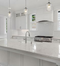 a large kitchen with white cabinets and marble counter tops, along with stainless steel appliances