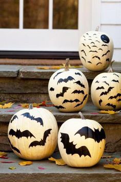 four pumpkins with bats painted on them are sitting on the steps next to each other