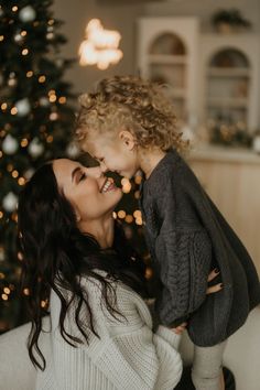 a woman holding a child in front of a christmas tree