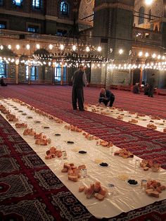 people are standing in the middle of a room with many plates and food on it