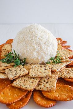 cheese ball on top of crackers with sprig of thyerole in the middle