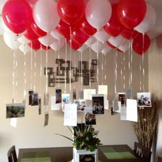 a bunch of balloons hanging from the ceiling above a dining room table with pictures on it