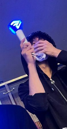 a person holding a toothbrush up to their face in front of a blue light