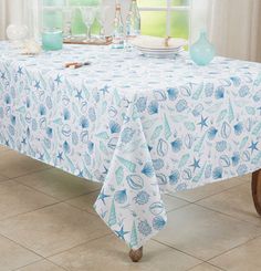 a blue and white table cloth with seashells on it in front of a window