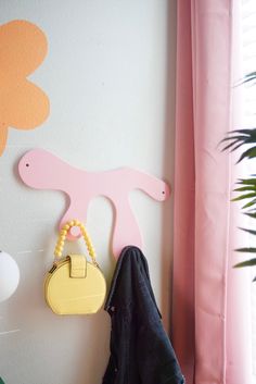 a coat rack with a purse hanging on it next to a pink flowered wall