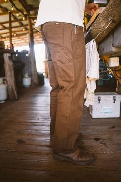 Strong, durable, and ready to roam. Made to be your everyday workhorse, the Bison Pant grazes with ease. Offered in a heavy weight rigid canvas, relaxed fit silhouette, & sturdy herringbone pocketing, this style gets better with time. Details include strongly made top entry seam belt loops, front pocket reinforced inset (that doubles as a knife clip), rear utility pockets for accoutrements, signature side sunglass loop, and hard wearing triple-needle at side seams & center back seam. Fit: Model Rugged Straight Leg Bottoms For Everyday, Rugged Bottoms With Pockets For Fall, Rugged Fall Pants With Pockets, Rugged Relaxed Fit Cotton Bottoms, Rugged Relaxed Fit Straight Leg Bottoms, Rugged Straight Leg Pants For Fall, Brown Tapered Leg Chinos With Pockets, Brown Tapered Leg Jeans With Welt Pockets, Rugged Cotton Bottoms With Hip Pockets