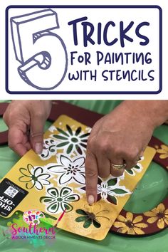 a person is painting with stencils on a yellow and green tablecloth that says 5 tricks for painting with stencils