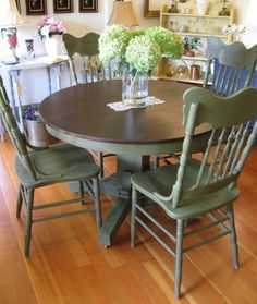 a dining room table with green chairs and pictures on the wall behind it, along with wooden flooring