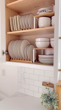 the dishes are stacked on wooden shelves in the kitchen