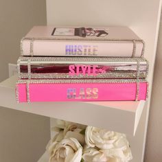 three books stacked on top of each other with flowers in the foreground and white roses in the background