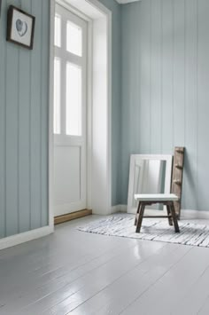 a white chair sitting on top of a hard wood floor next to a door and window